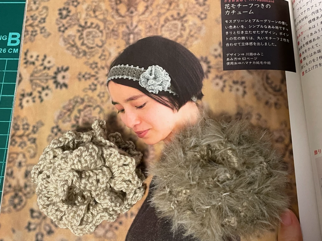 川路ゆみこさんデザイン、花モチーフつきのカチューム作品画像。編んだ花モチーフブローチも添えて撮影
