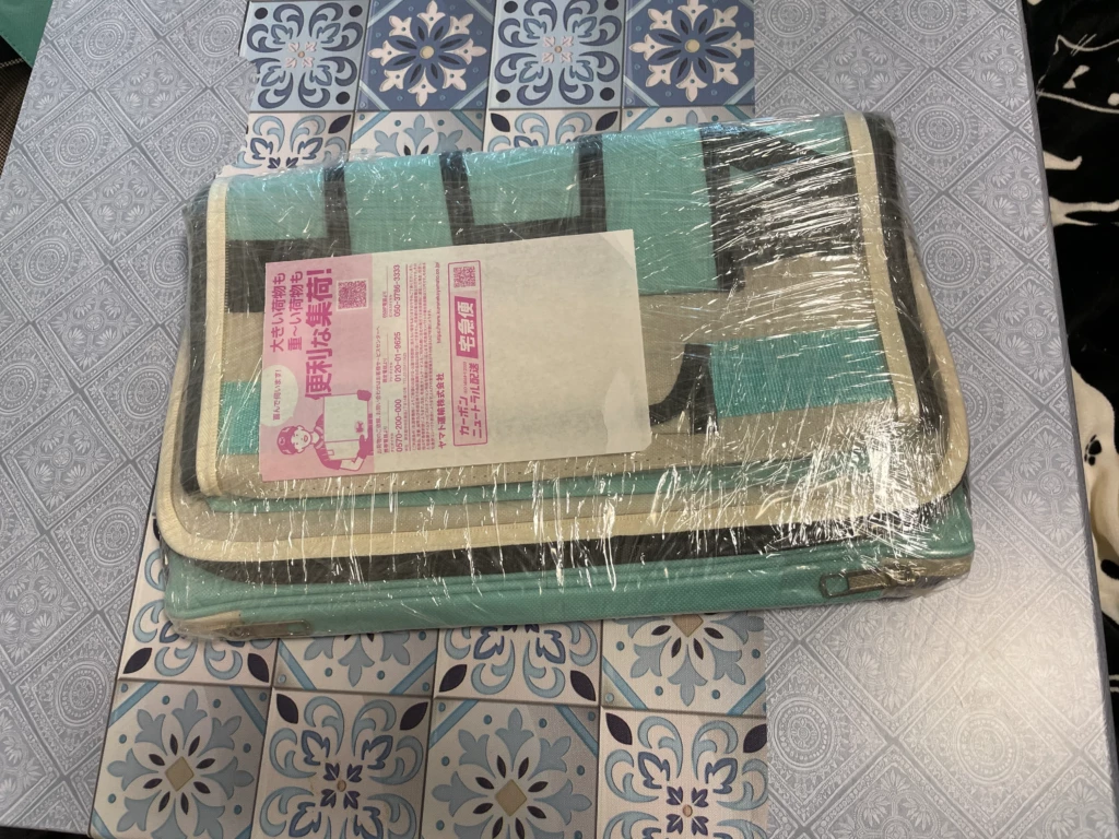 簡易包装で届いたキャリーバッグ外観。透明なビニールの上から透明なラップ状のものでぐるぐる巻きにされて宛名シールが貼られている